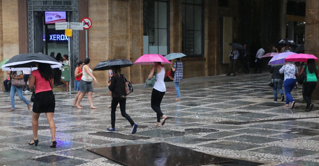Pessoas andando na rua durante chuva