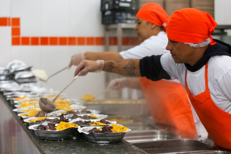 Cozinheiros servindo comida nas marmitas, alimentação